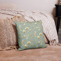 Turquoise & Gold Magnolia Dreams decorative pillow featuring magnolias, hummingbirds and butterflies in a muted gold tone styled against a cosy sofa and pillows in a neutral, beige colour