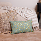 Turquoise & Gold Magnolia Dreams decorative pillow featuring magnolias, hummingbirds and butterflies in a muted gold tone styled against a cosy sofa and pillows in a neutral, beige colour