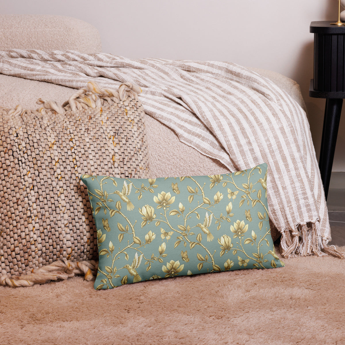 Turquoise & Gold Magnolia Dreams decorative pillow featuring magnolias, hummingbirds and butterflies in a muted gold tone styled against a cosy sofa and pillows in a neutral, beige colour