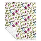 Magnolia Dreams throw blanket with a white background, featuring pink magnolia flowers, colorful hummingbirds, butterflies and green leaves