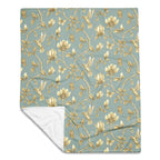 Magnolia Dreams Gilded Garden throw blanket in Turquoise & Gold, showcasing delicate magnolia blossoms, leaves and butterflies