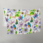 Garden of Eden throw blanket hanging on a line, featuring colorful flowers, kingfishers, bumblebees, leaves and berries