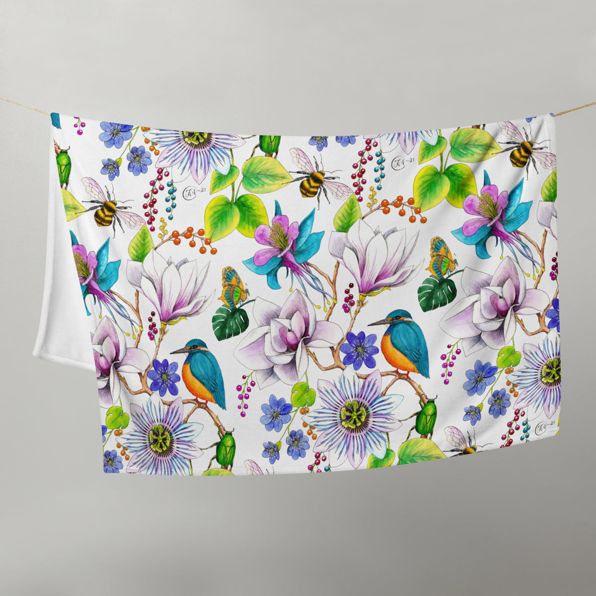 Garden of Eden throw blanket hanging on a line, featuring colorful flowers, kingfishers, bumblebees, leaves and berries