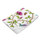 Magnolia Dreams throw blanket displaying pink magnolia blossoms, colorful hummingbirds, butterflies and green leaves on a white background
