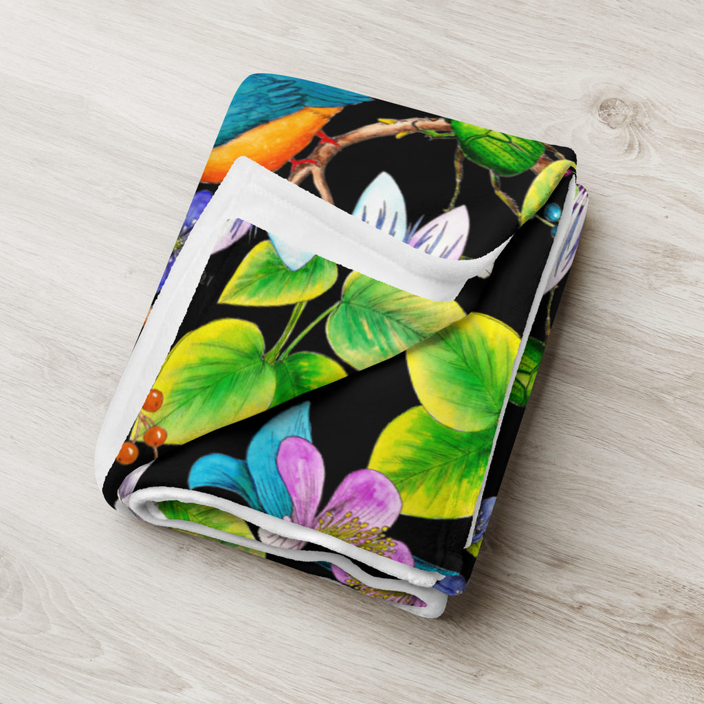 Folded Garden of Eden throw blanket featuring an exotic kingfisher, colorful flowers, green leaves and berries on a black background