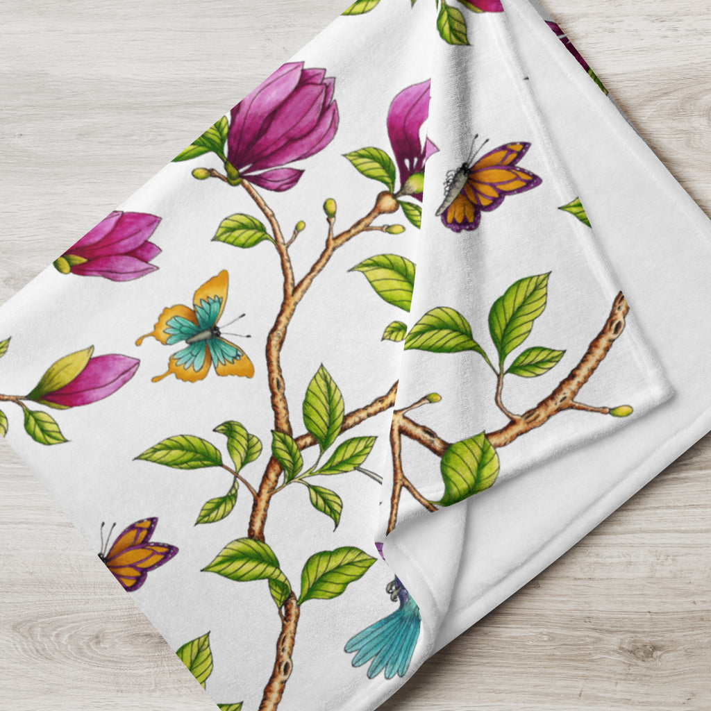 Close-up of a Garden of Eden throw blanket showing a colorful kingfisher, magnolia flowers, berries and green leaves on a black background