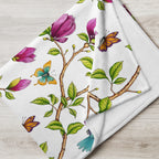 Close-up of a Garden of Eden throw blanket showing a colorful kingfisher, magnolia flowers, berries and green leaves on a black background
