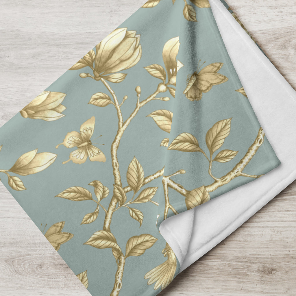 Magnolia Dreams Gilded Garden throw blanket in Turquoise & Gold, draped over a sofa
