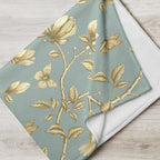 Magnolia Dreams Gilded Garden throw blanket in Turquoise & Gold, draped over a sofa