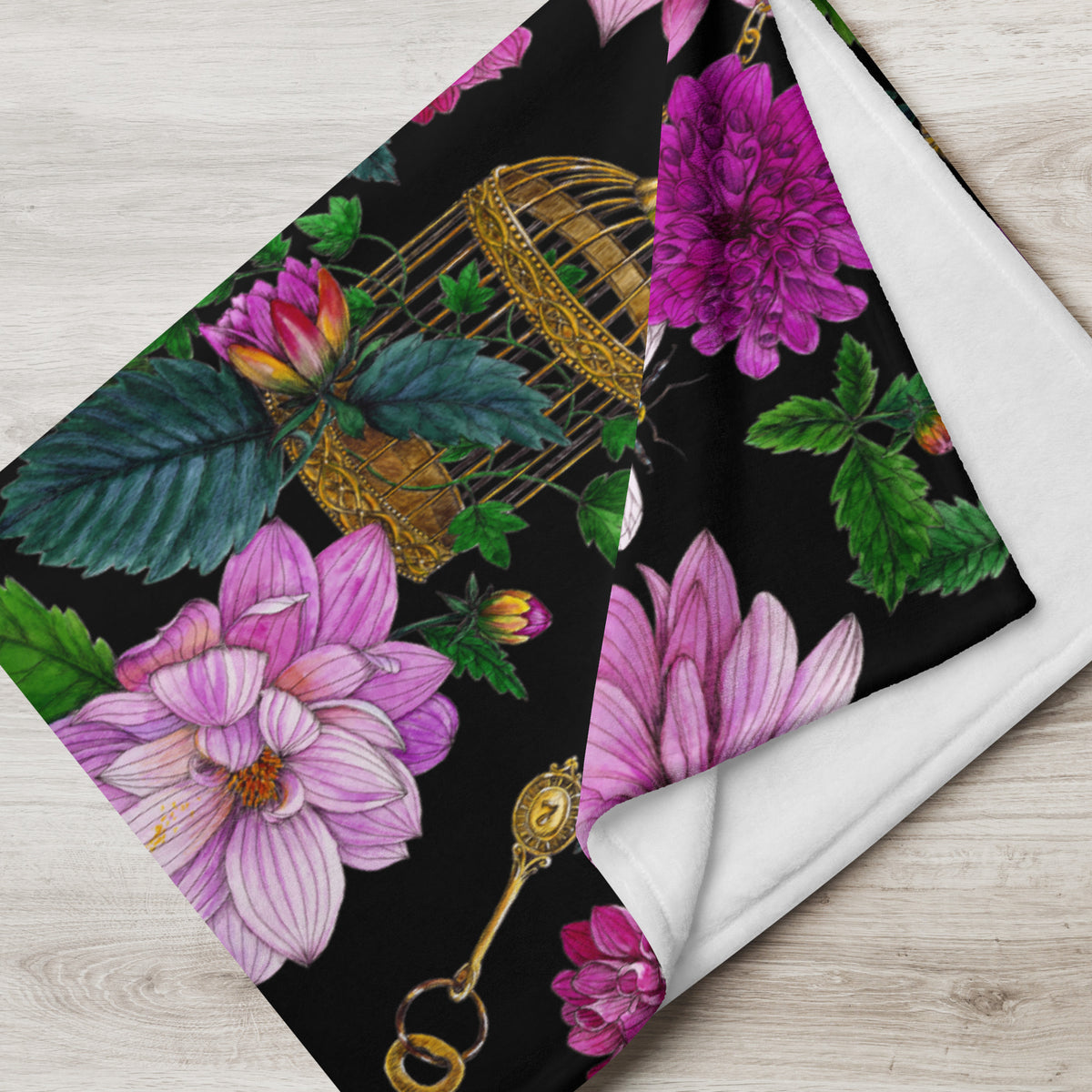Close-up of a throw blanket featuring the Dahlia Garden pattern, showing colorful flowers, leaves and a decorative birdcage